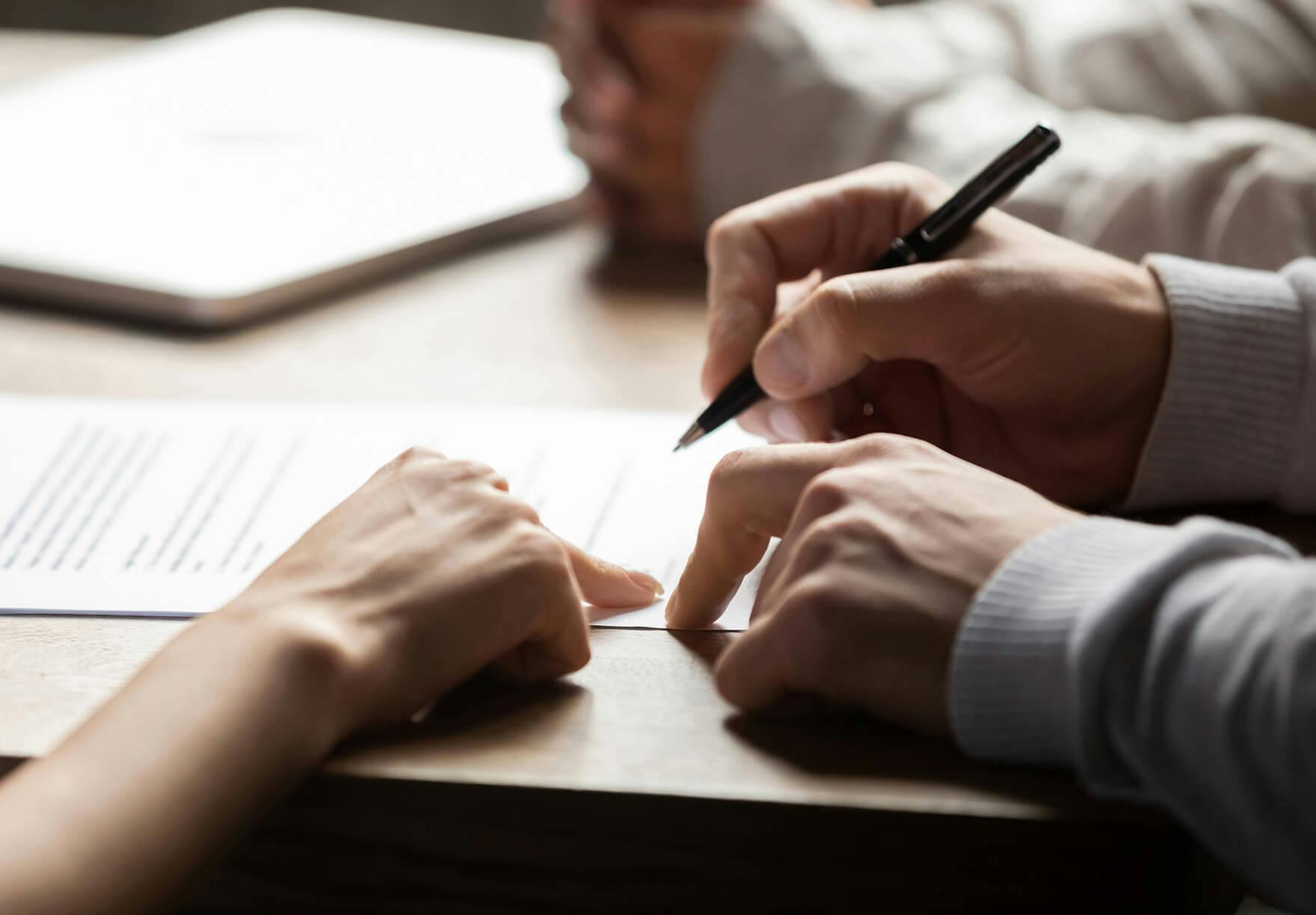 Two people signing a document at a table.