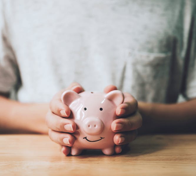 A person holding a piggy bank filled with fair price guarantee savings