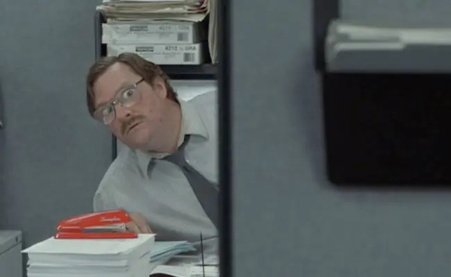Milton from Office Space sitting with his stapler