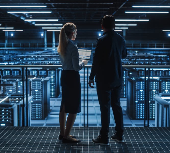 Two people standing in front of a server room.