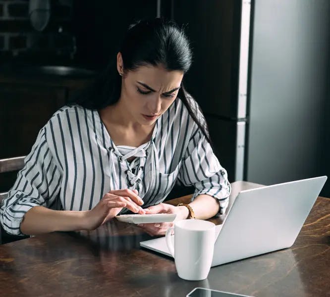 Woman working from home and using a calculator while confused about payroll tax requirements