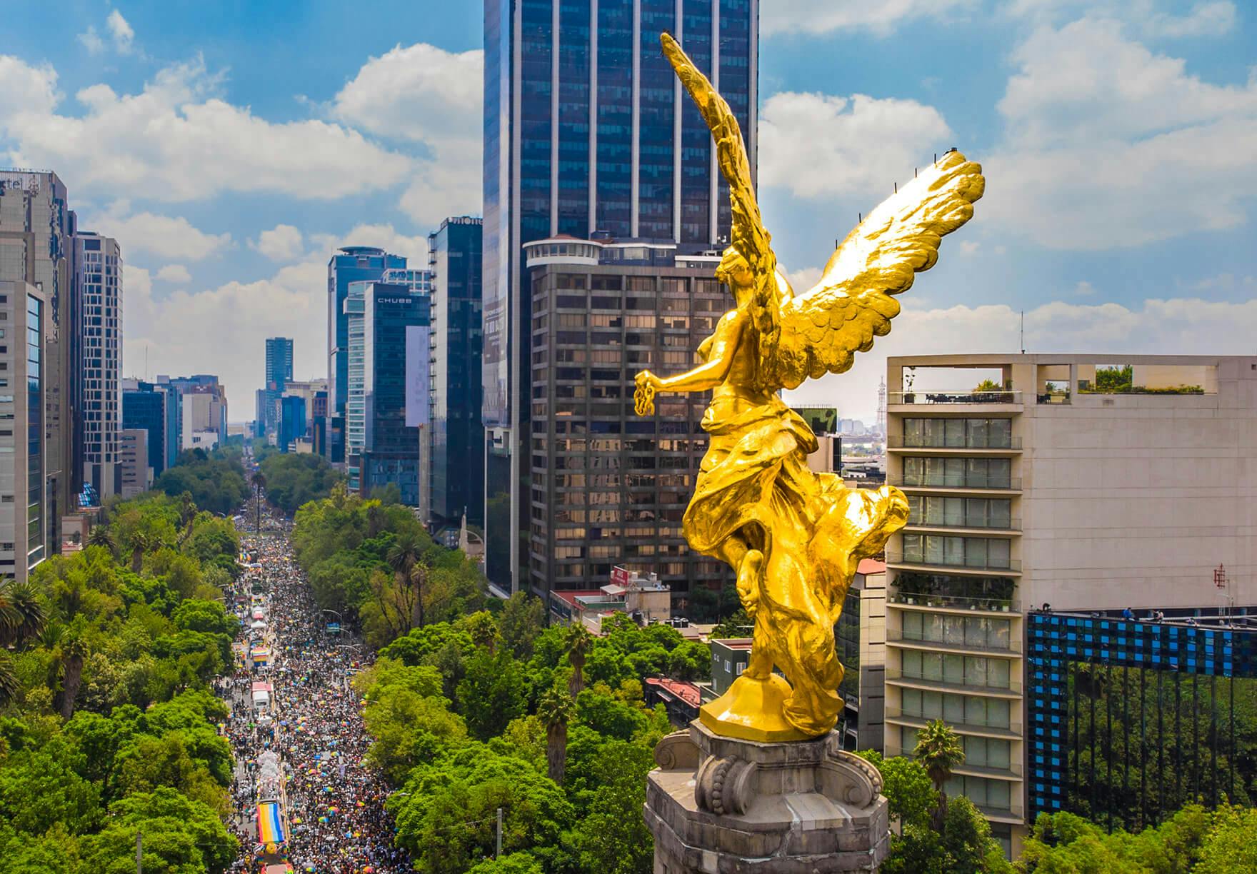 A golden statue of an angel in the middle of a city.