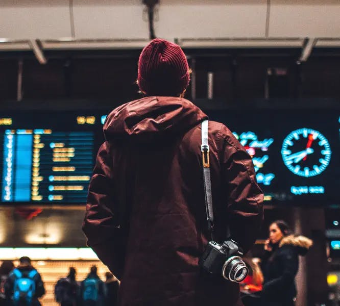 Man standing at an airport looking at signs