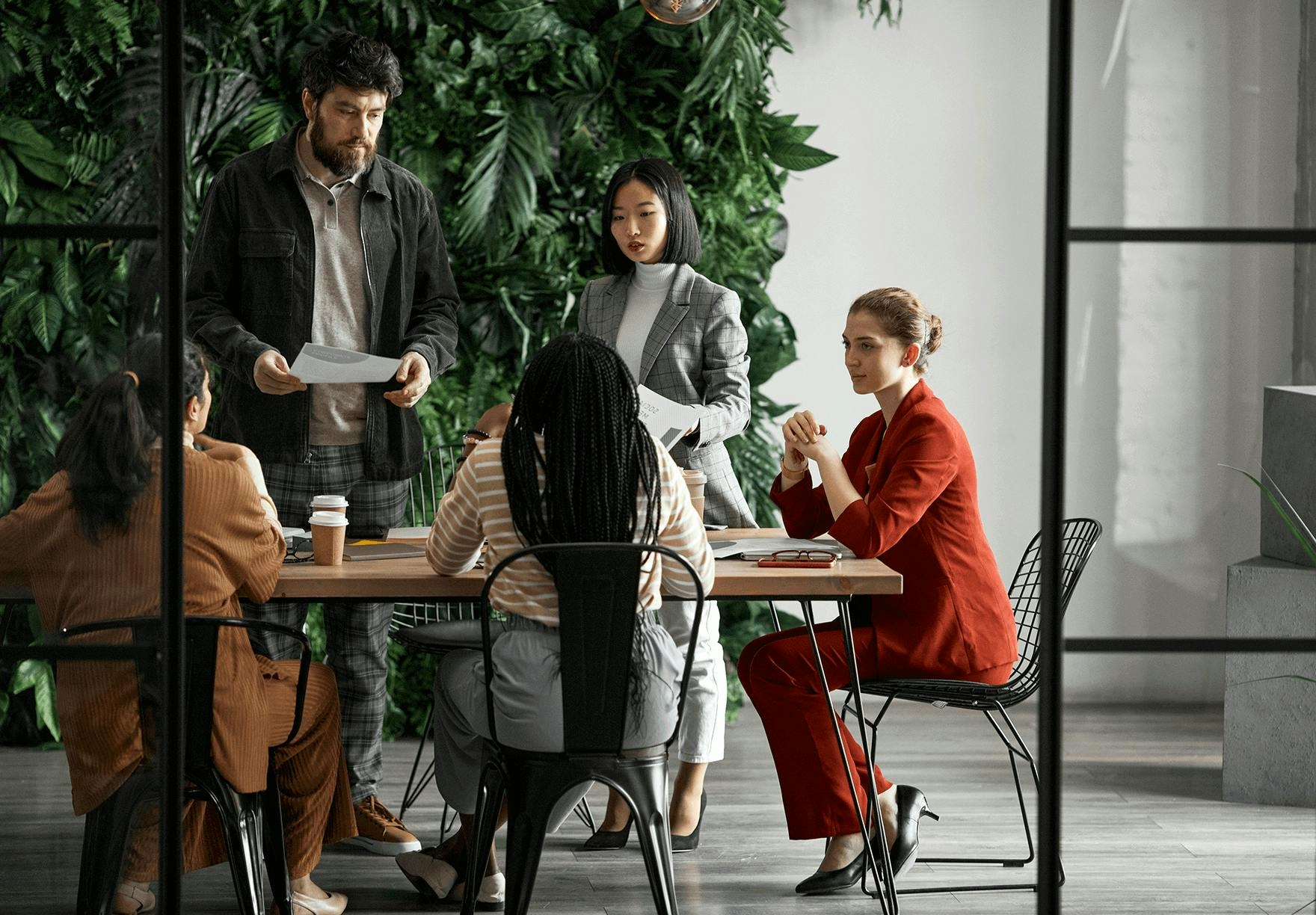 A group of people gathering at a table with documents and coffee