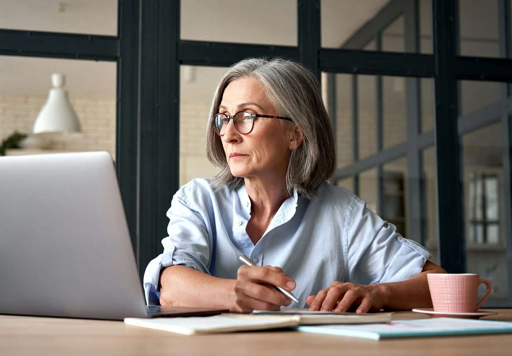 An older woman pensively fills out a form